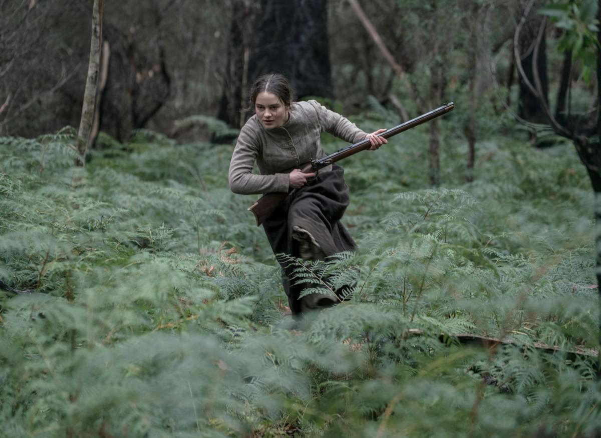 Clare (Aisling Franciosi) racing through a forest and touting a rifle in The Nightingale.
