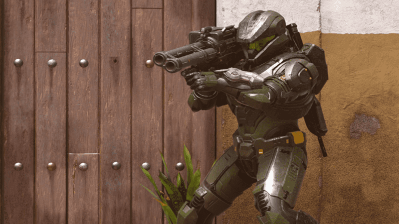 A Halo Spartan aims a rocket launcher with his back towards a basic wall.