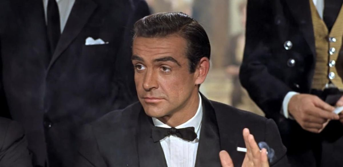 Sean Connery, in a tuxedo and holding a smoking cigarette, in Dr. No