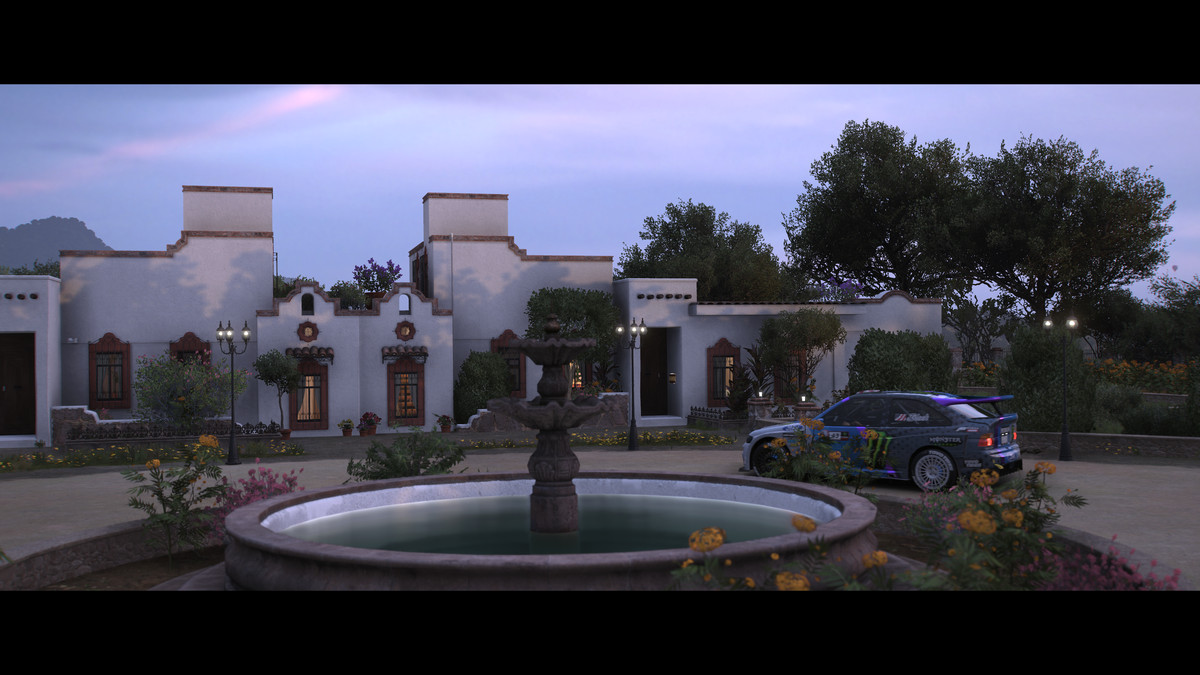 A rally car parked in the driveway outside a home done in Spanish architectural style