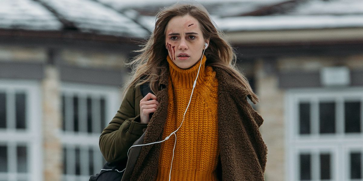 Suki Waterhouse in Seance, walking outdoors with open, bloody cuts on her forehead and cheek