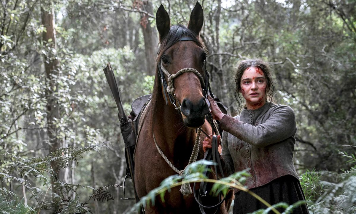 Clare (Aisling Franciosi) bloodied and walking through a forest with a horse in The Nightingale.