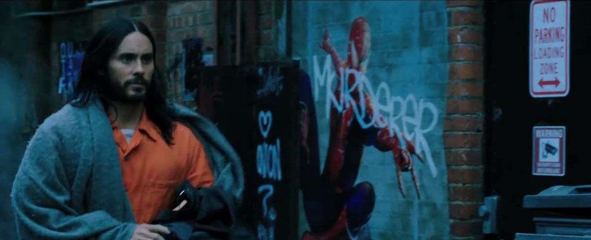 Jared Leto’s Morbius walks through an alley with a Spider-Man poster in the background 