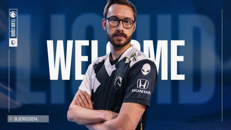 Pro LoL player Soren “Bjergsen” Bjerg stands with his arms crossed in a TL jersey with the words "Welcome" and "Liquid" in the background behind him.