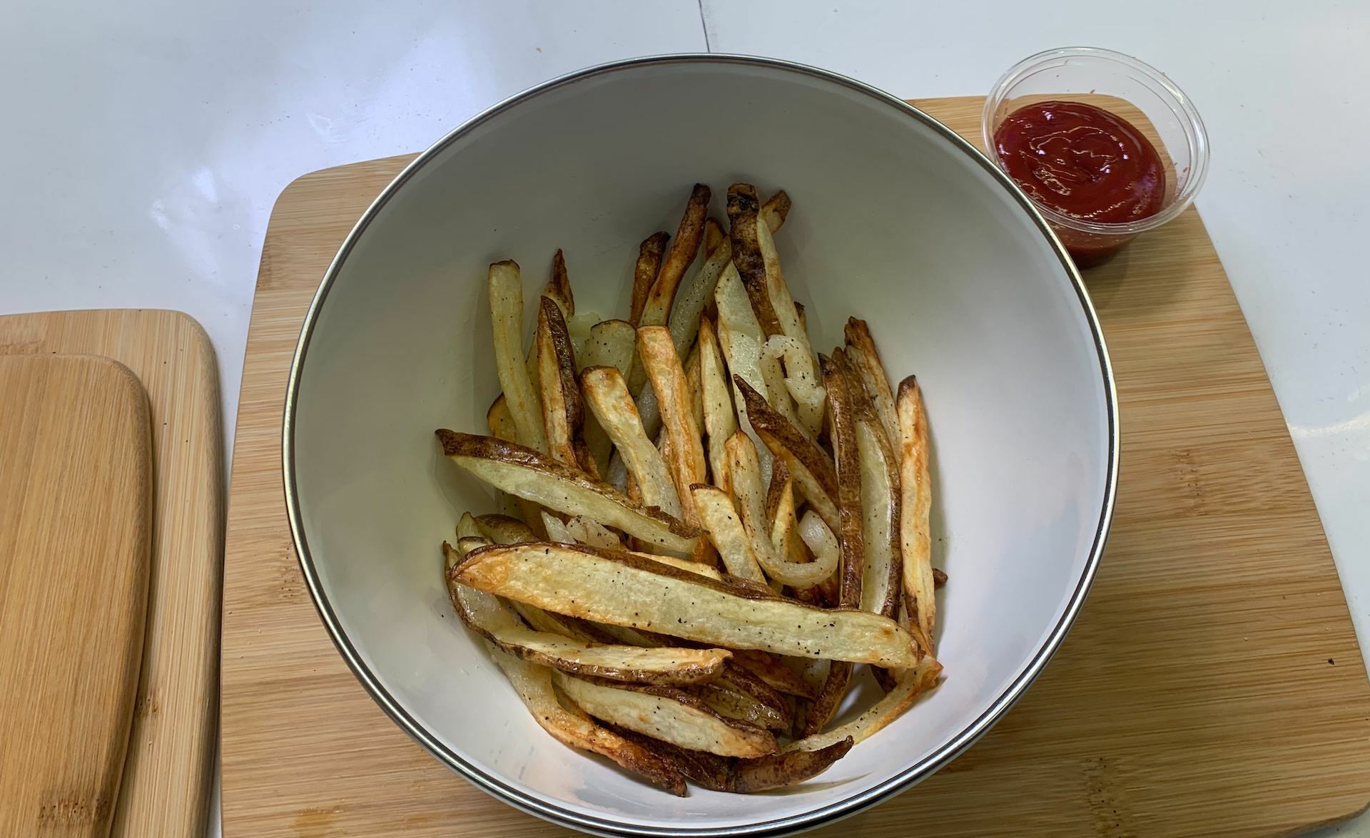 cooked fries in bowl with ketchup on side