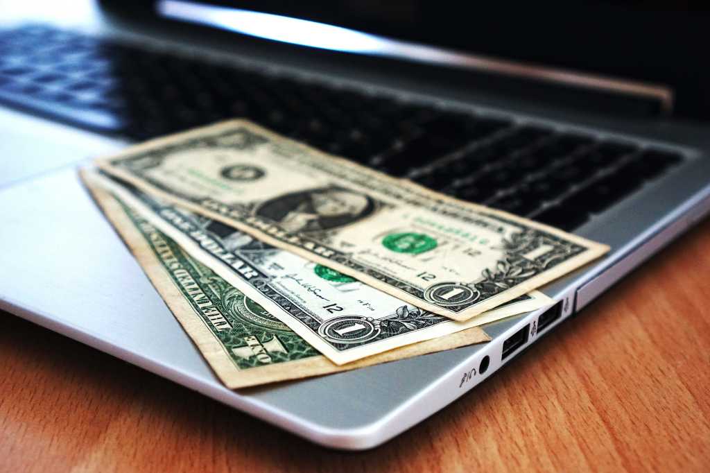 Dollar bills on top of an open laptop