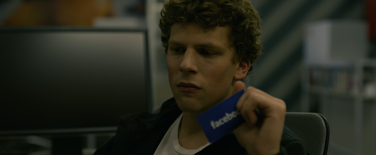 Jesse Eisenberg holds a card with the Facebook logo in The Social Network.