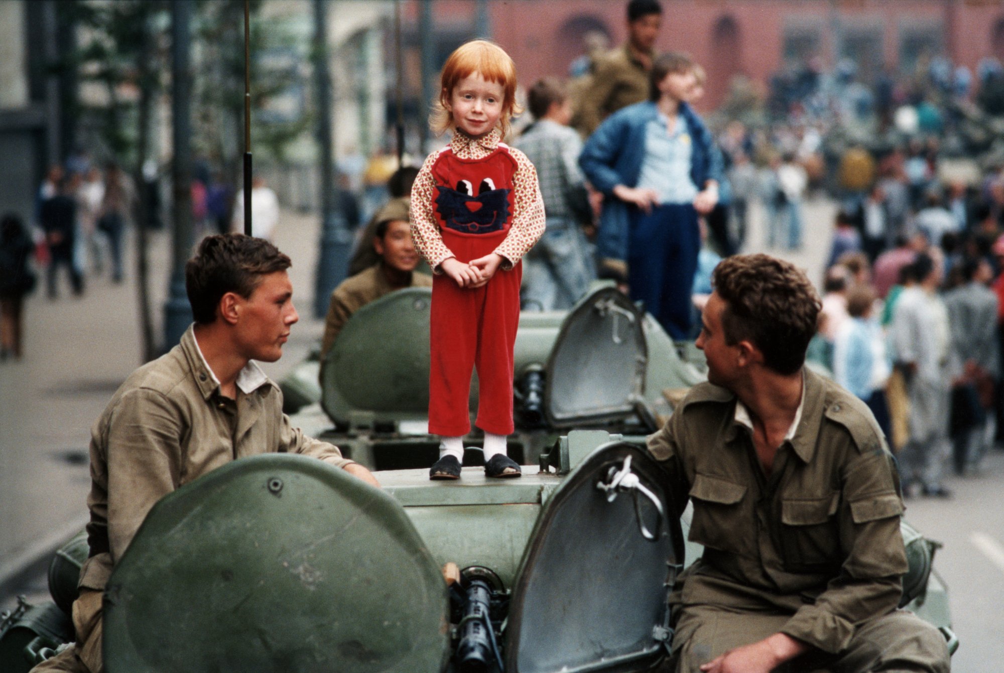 A little girl stands placidly atop a Soviet tank in the barricades at Red Square during the coup.
