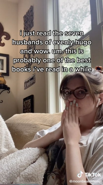A girl covers her mouth with her hands, discussing her love for a book.