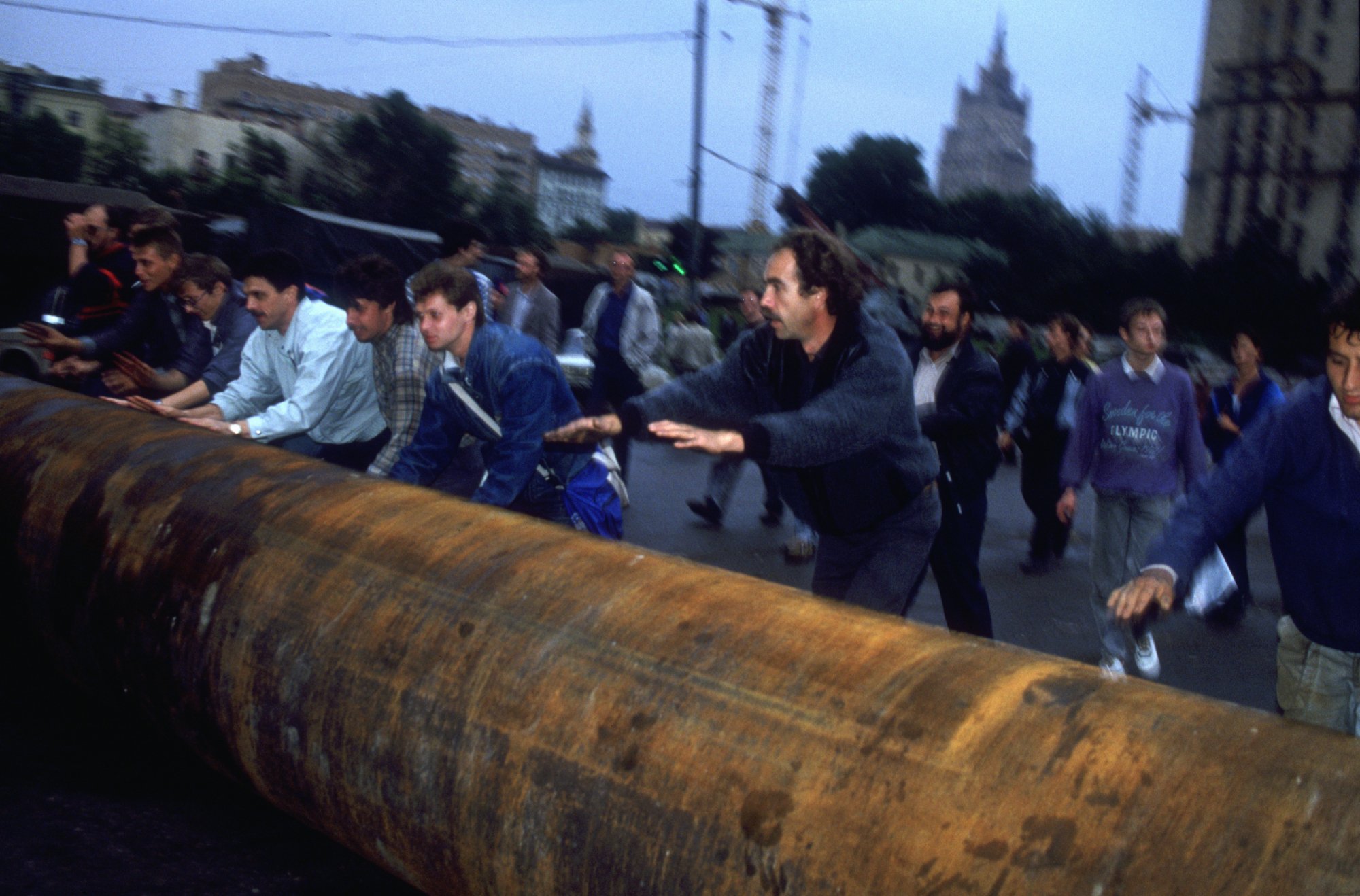 Demonstrators roll a large metal pipe through the streets of Moscow to help form a barricade outside the Russian White House.
