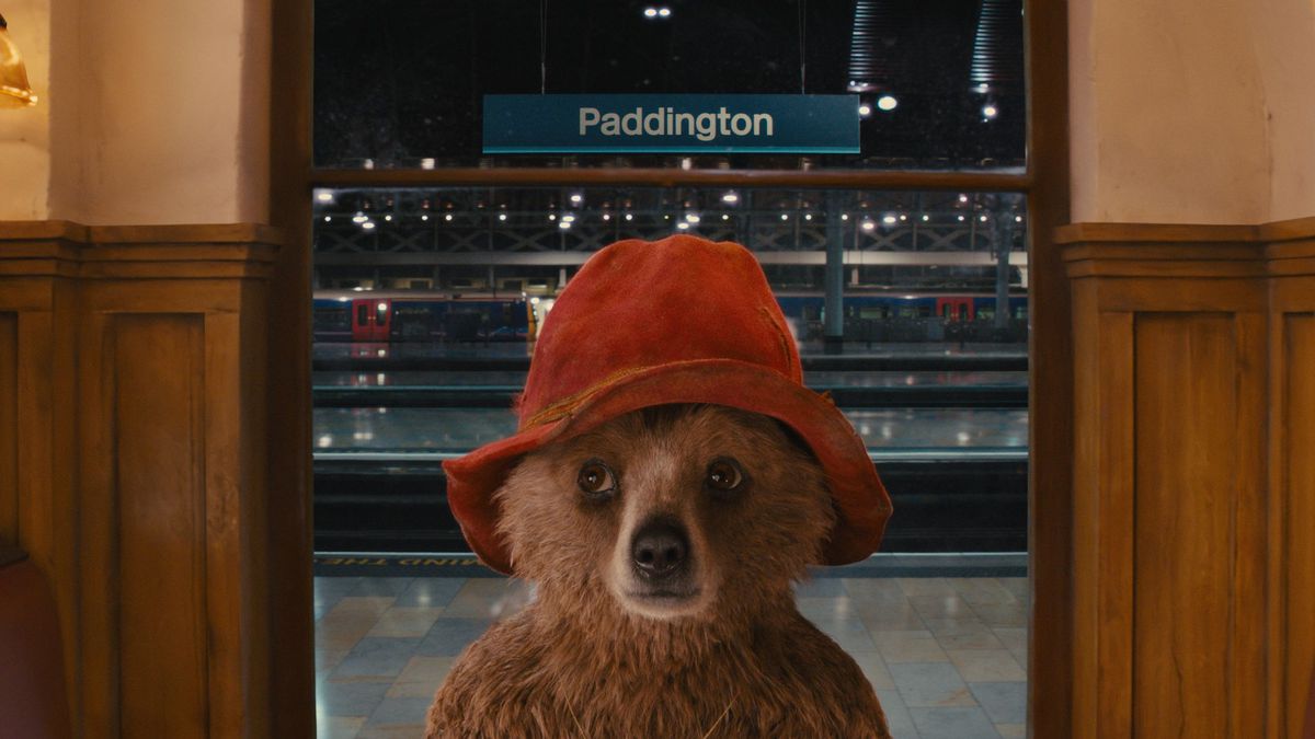 Paddington standing in front of his namesake: a subway sign for Paddington station in Paddington (2014).