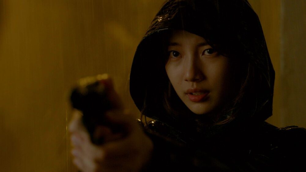 Bae Suzy wears a raincoat and holds a gun in Vagabond.
