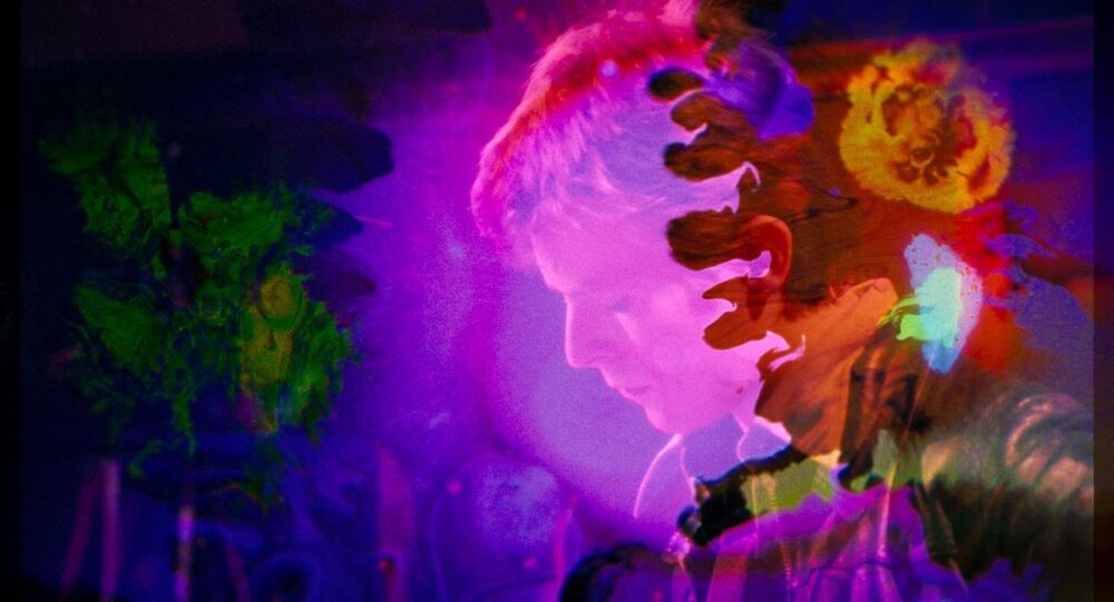 A young David Bowie’s face appears through swirling splashes of purple and orange in Moonage Daydream