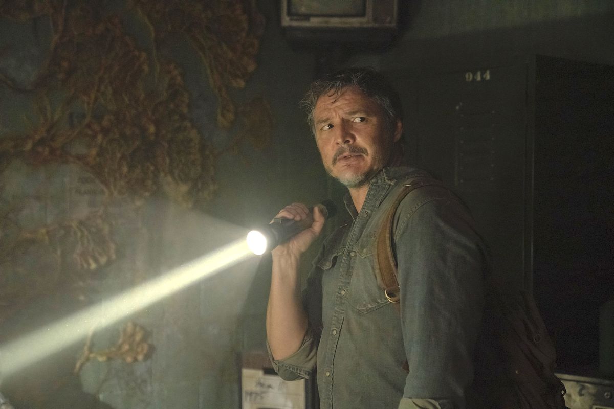 Pedro Pascal as Joel holds up a flashlight in a moldy dark room in the HBO show The Last of Us