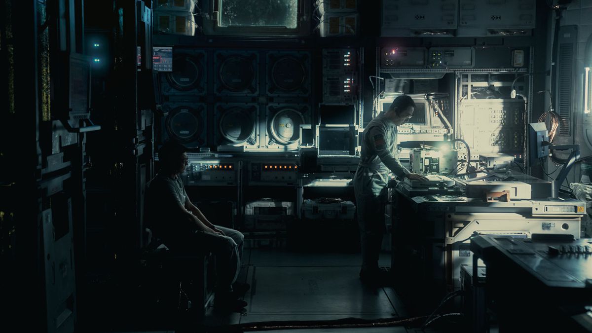 A man bends over a table to look at something in a dark, futuristic-looking science lab in The Wandering Earth II