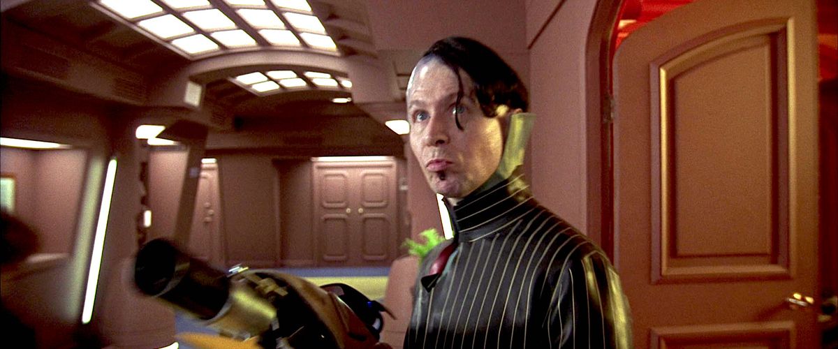 Zorg brandishes an alien weapon while storming through the hallway of a hotel hallway