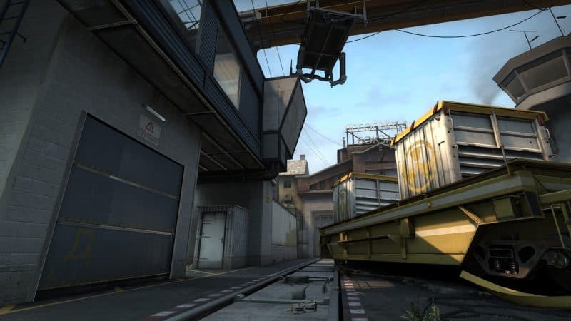 An abandonned railway gondola sits askew across the tracks on CS:GO's Train map. Shipping containers are strewn around the isolated outpost.