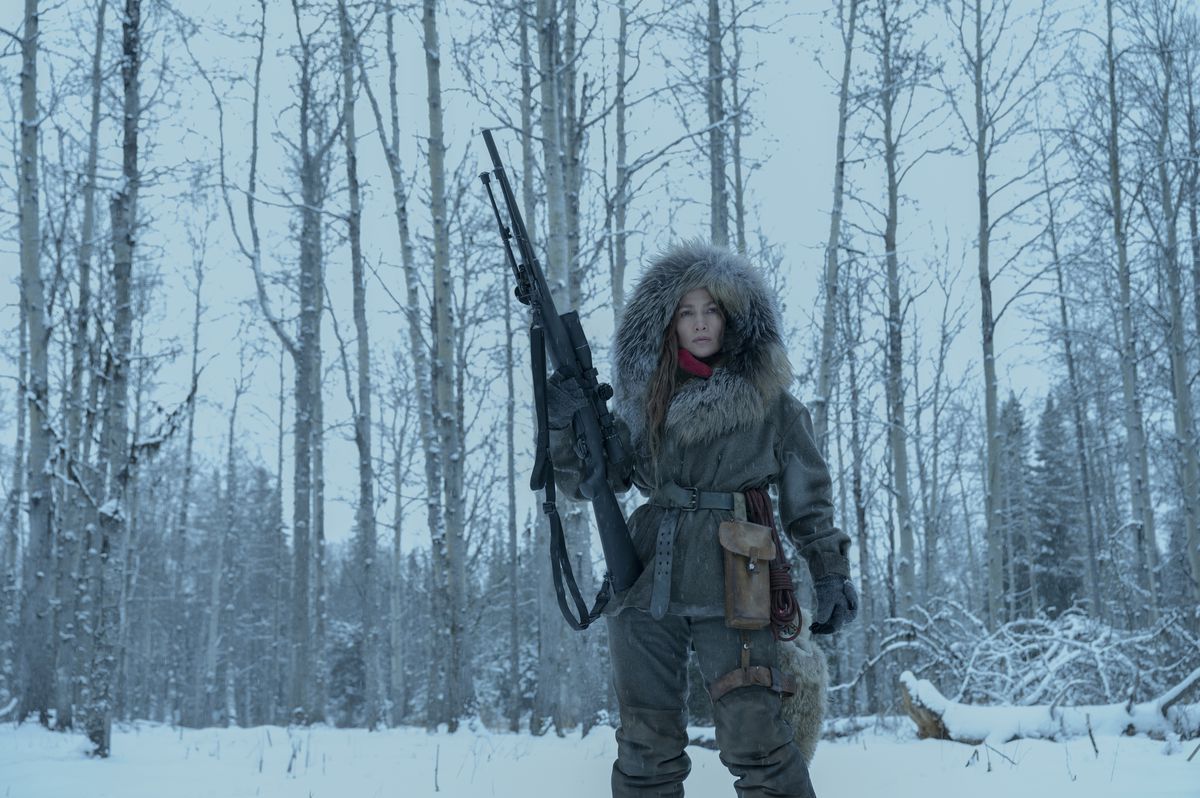 Jennifer Lopez as “The Mother,” an assassin wearing a winter coat holding a rifle against her hip, in The Mother.