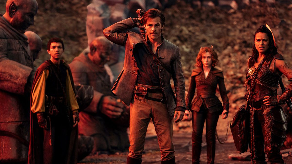 (L-R) The half-elf sorcerer Simon (Justice Smith), the human Bard Edgin (Chris Pine), the tiefling&nbsp;druid Doric (Sophia Lillis), and the Barbarian warrior Holga (Michelle Rodriguez) standing in a valley flanked by solemn looking statues in Dungeons &amp; Dragons: Honor Among Thieves.