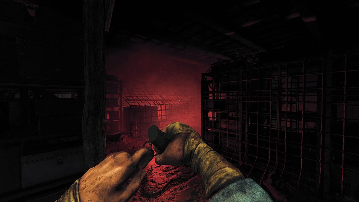 The protagonist prepares to throw a grenade in a flare-lighten corridor in Amnesia: The Bunker