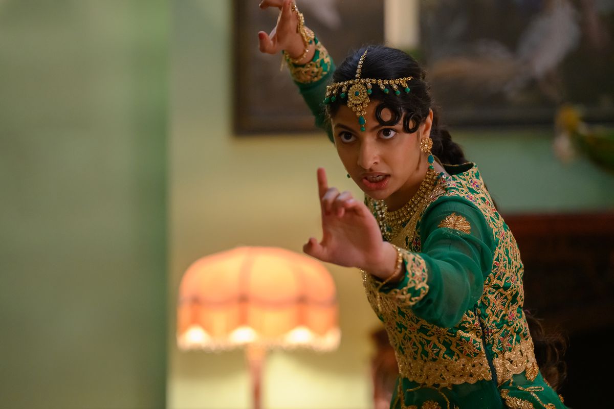 ریا، یک نوجوان پاکستانی با لباس سنتی رقص سبز و طلایی، دستانش را در حالت جنگی دراز کرده است.