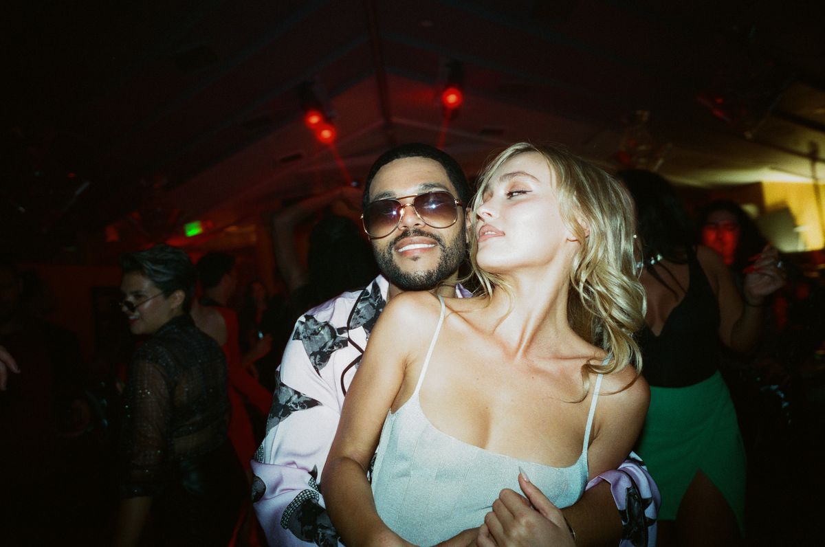 Tedros (Abel “The Weeknd” Tesfaye) hugs Jocelyn (Lily Rose-Depp) from behind in a photo that’s meant to look like it was taken with a flash camera in a nightclub, from the HBO series The Idol.