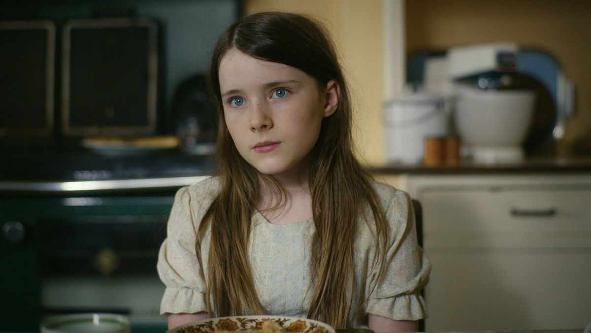 Catherine Clinch as Cáit sitting at a table in The Quiet Girl.