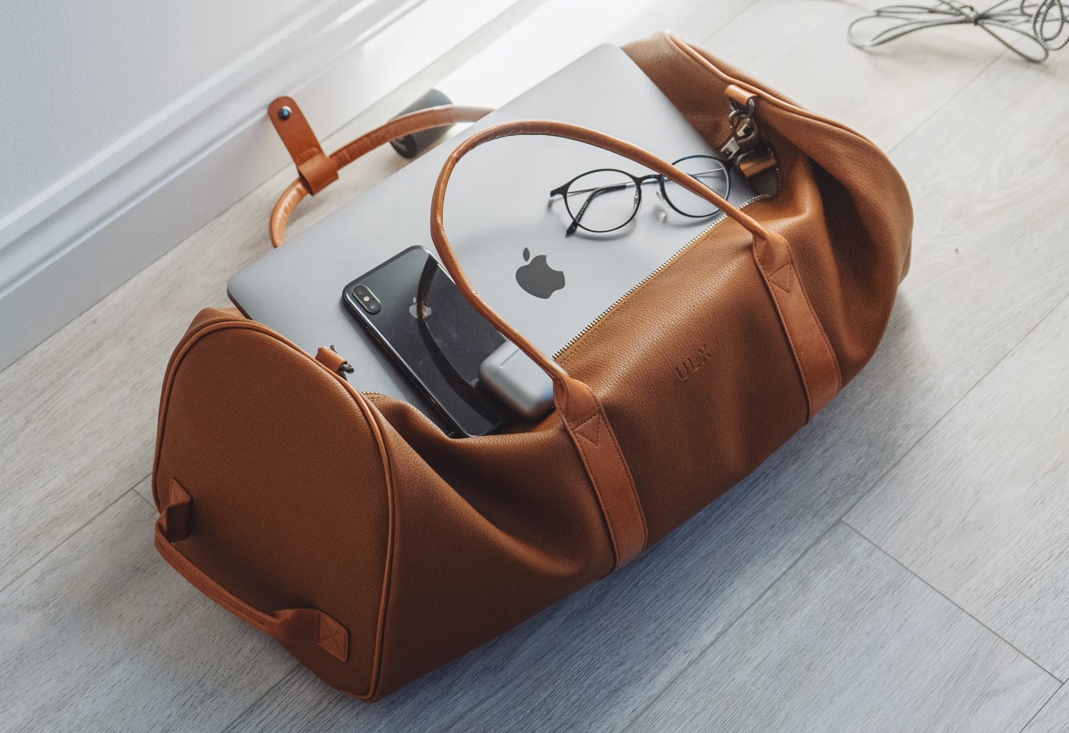 Duffel bag with iPhone, MacBook, and Airpods