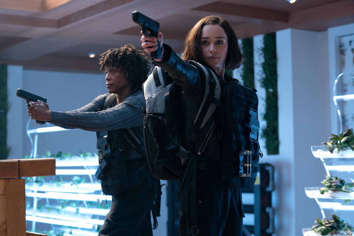 (L-R): Charlayne Woodard as Priscilla Davis/Varra and Emilia Clarke as G’iah brandish guns and wear body armor in an indoor space with lots of plants in Secret Invasion.