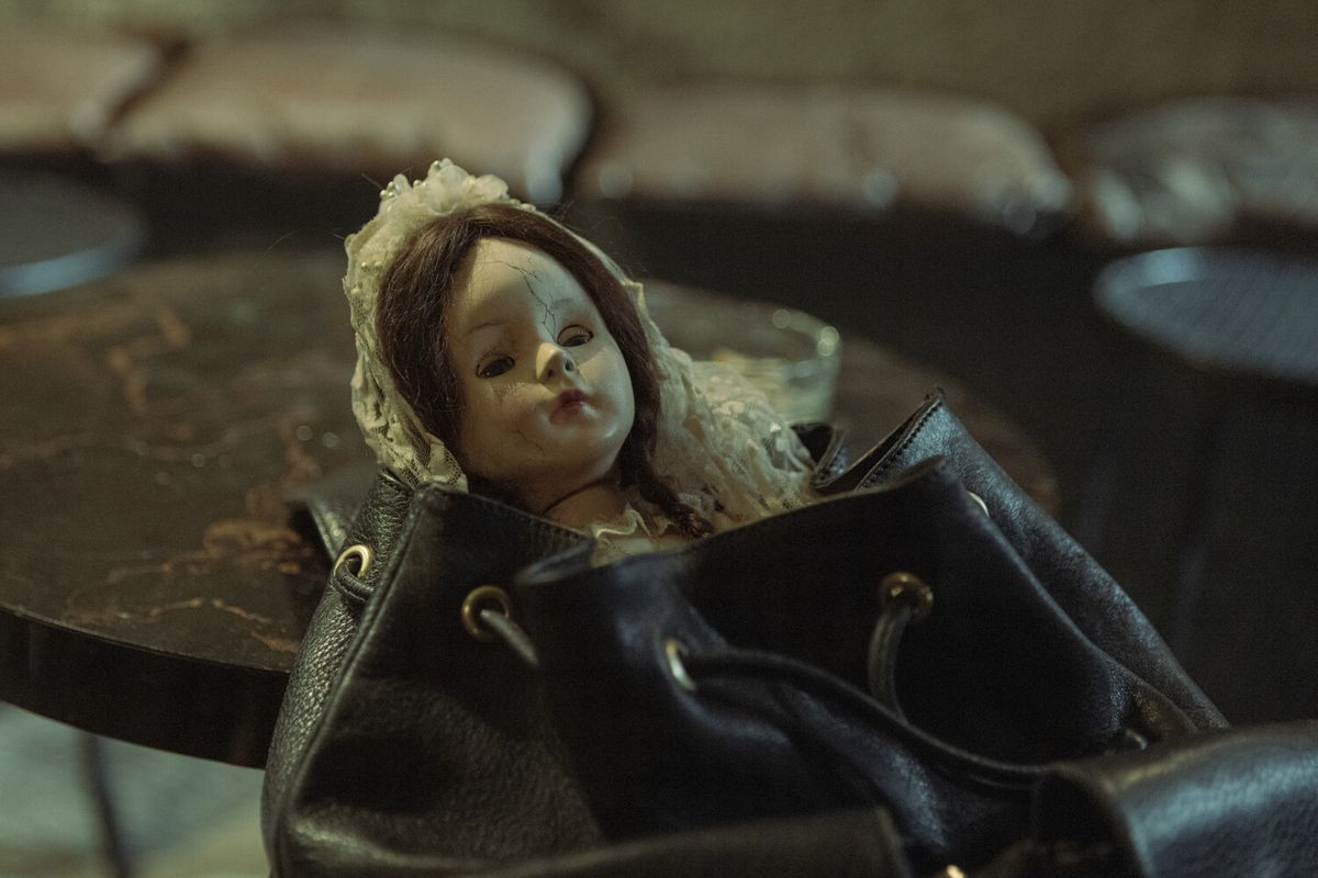 A creepy doll dressed in communion garb peaks out of a purse in The Communion Girl.