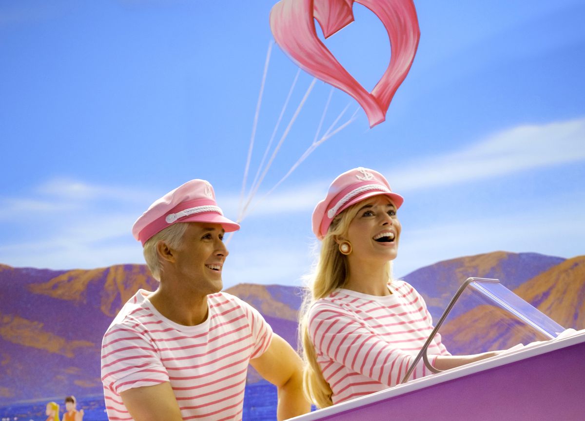 Barbie (Margot Robbie) and Ken (Ryan Gosling) beam hugely as they ride a bright-pink plastic Barbie boat across an artificial sea in the 2023 live-action Barbie
