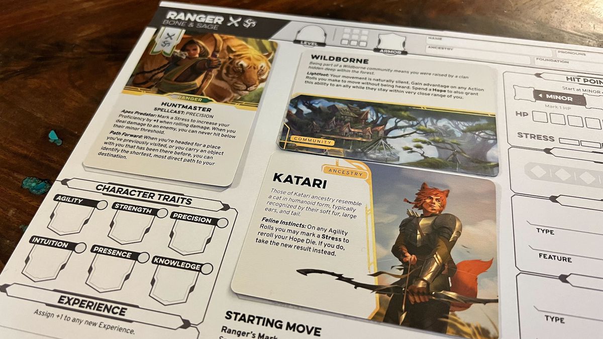 A close-up of the card-based character sheet in Daggerheart. One card, for Huntmaster, calls out the class. Another, for Katari, calls out the ancestry of the character, while another — wildborne — notes the community to which it belongs.