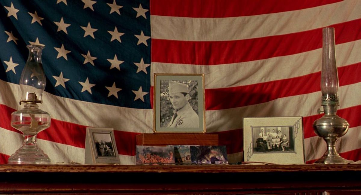 An American flag with framed pictures of Viggo Mortensen in uniform, from The Reflecting Skin.