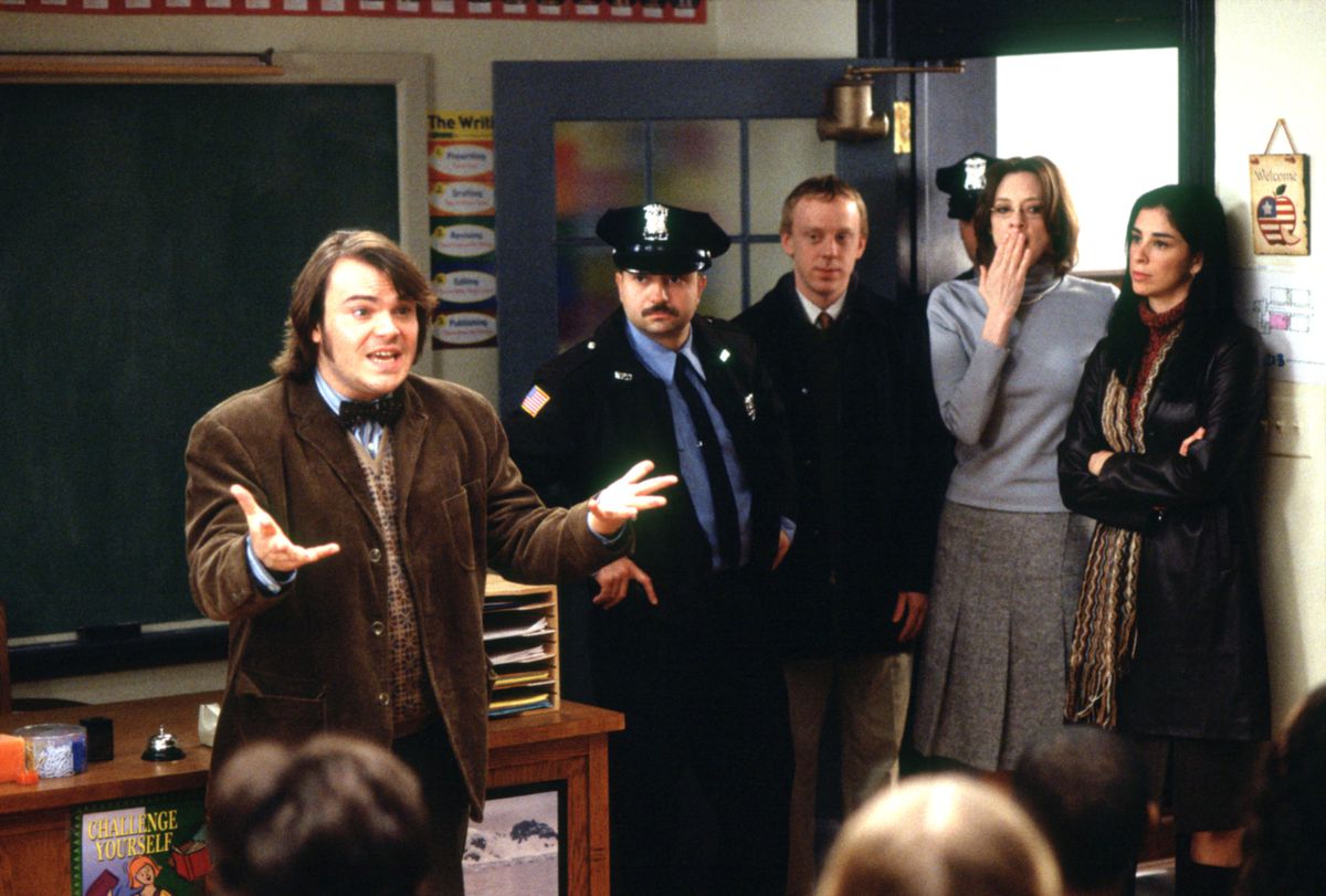 Jack Black, in a brown tweed suit jacket, makes a vocal appeal to his classroom as a cop and several administrators enter the room in Richard Linklater’s 2003 movie School of Rock