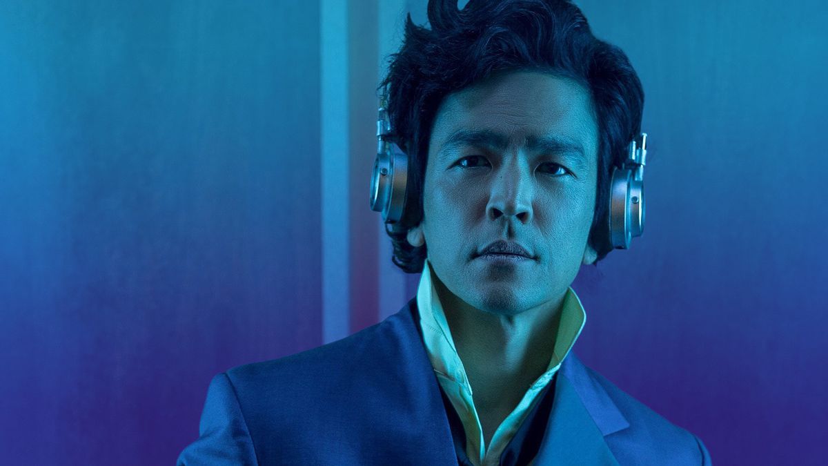 Photo of a man wearing headphones standing against a blue background