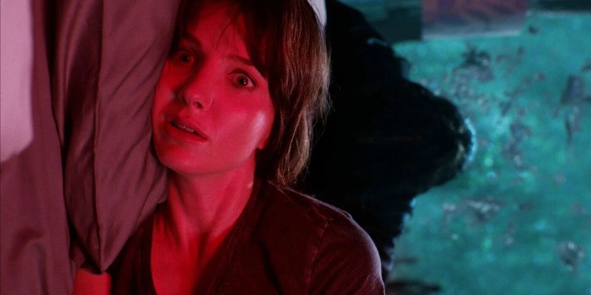 عکس کناری از آنابل والیس در حالی که مدیسون با رنگ قرمز روشن می شود و سایه ای مرموز بر تخت او در فیلم بدخیم شناور است.