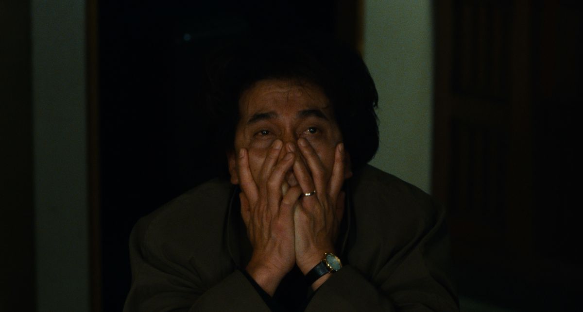 کارآگاه تاکابه (کوجی یاکوشو) در «درمان» (1997) از شدت خستگی و وحشت دست‌هایش را روی صورتش می‌بندد.
