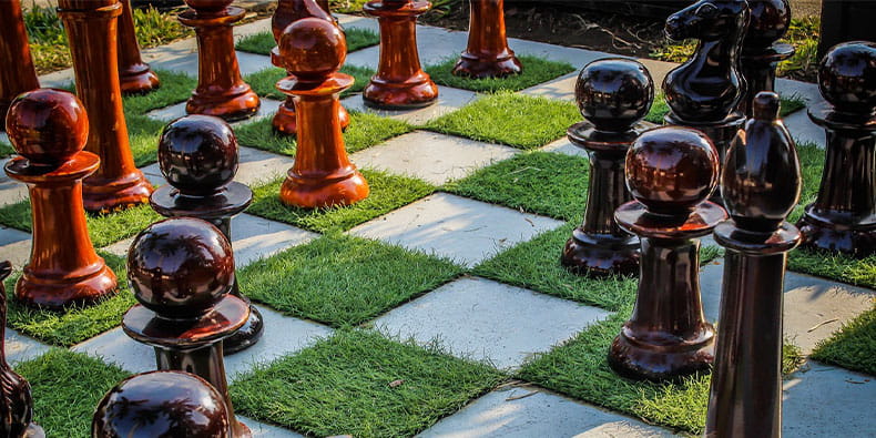 Chess Pieces on Grass Covered Playing Board