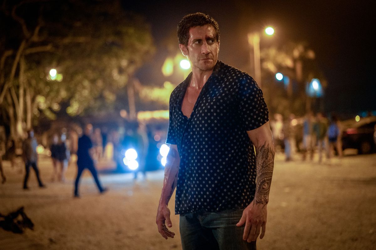 A man in a button-up shirt standing in a street at night.