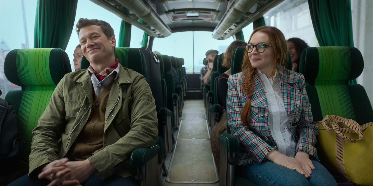 A smiling man and woman seated across from one another on a bus in Irish Wish.