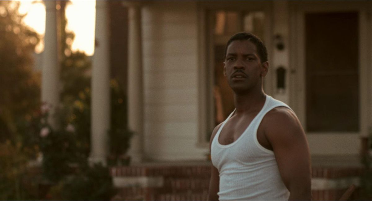 Denzel Washington, wearing a sleeveless top, stands in front of a house in Devil in a Blue Dress