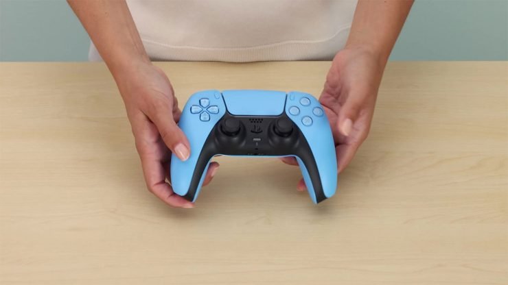 An image showing a person holding the PlayStation 5 DualSense Startlight Blue, an alternative controller design for the PlayStation 5