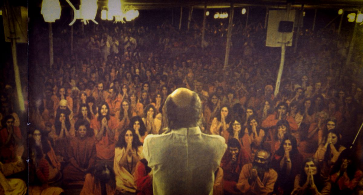 A slightly grainy, older image of a meeting led by Guru Bhagwan Shree Rajneesh from Wild Wild Country
