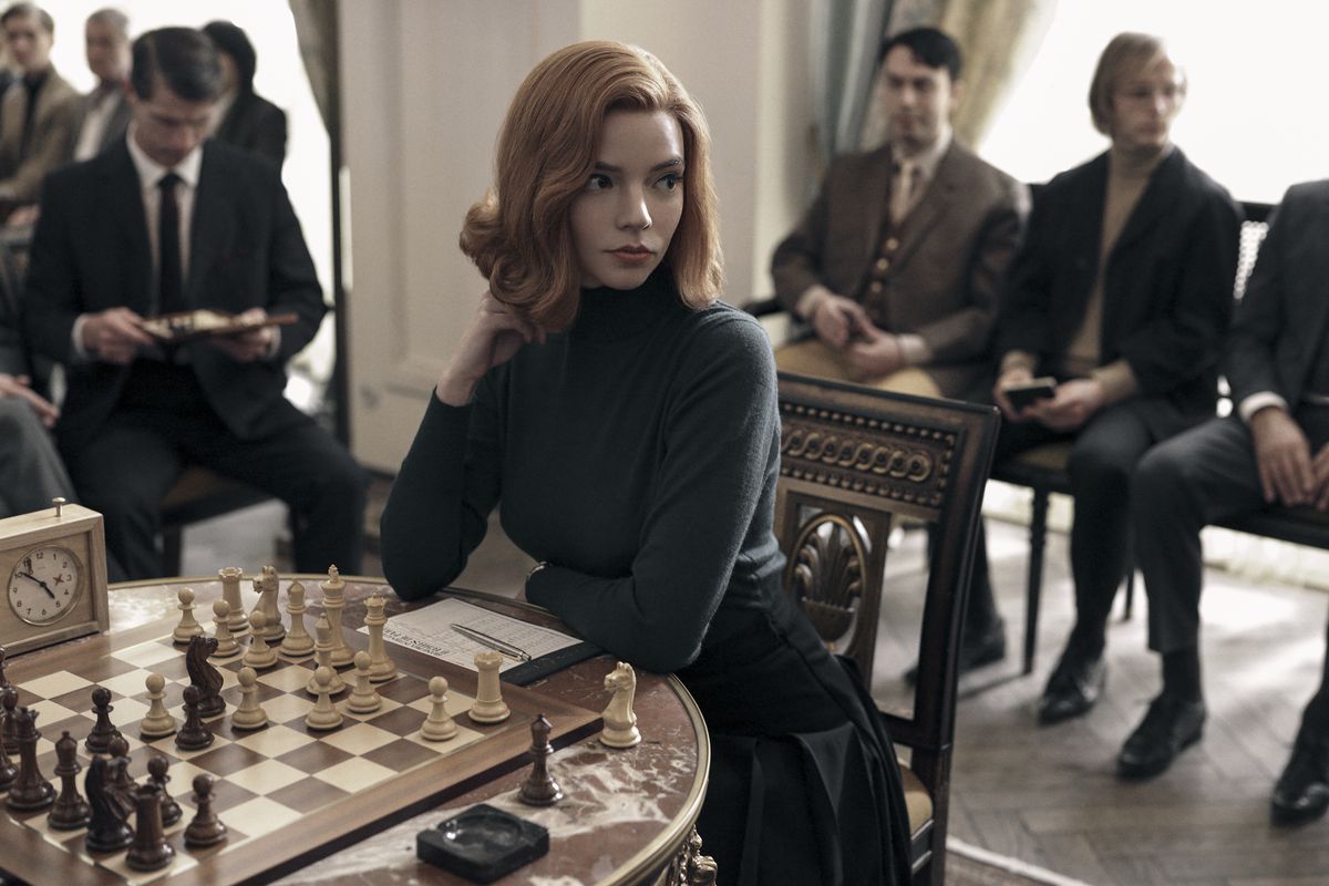 بازی Queen's Gambit: Anya-Taylor Joy روی صفحه شطرنج می نشیند و مردها اطراف آن را احاطه کرده اند.
